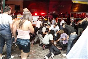 People help an injured man at the scene of the fire at the Kiss nightclub. Survivors said party-goers panicked and many victims became disoriented by the thick smoke.
