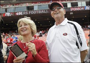 Jackie and Jack Harbaugh, parents of San Francisco 49ers coach Jim Harbaugh and Baltimore Ravens coach John Harbaugh, stand before an NFL football in 2011