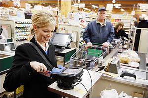 Cherie McHue of Toledo uses her credit card to pay for purchases Tuesday at The Anderson’s in Toledo. No extra fee was charged.