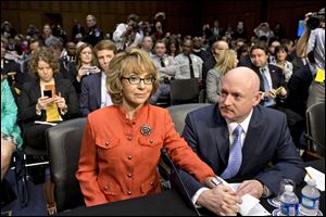 Former Arizona Rep. Gabrielle Giffords, who was seriously injured in the mass shooting that killed six people in Tucson, Ariz. two years ago, sits with her husband, Mark Kelly, right, a retired astronaut, on Capitol Hill in Washington.