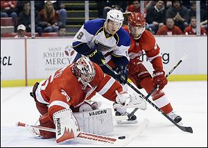 Red Wings goalie Jimmy Howard reaches for the puck in front of St. Louis’ Jaden Schwartz and Detroit defenseman Jakub Kindl.
