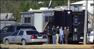 Law officers stand beside the Alabama State trooper mobile command post at the Dale County hostage scene in Midland City, Ala.
