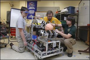 Freshman Brandon Coykendall, math teacher Dale Price and junior Joe Neyhart look over last year's robot during a robot club meeting at Toledo Technology Academy in Toledo, Ohio.