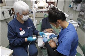 Dental assistant Penny Miklovic, left, and pediatrics resident Tracy Tran work on Alana Buck, 13, during the Toledo Dental Society’s Give Kids a Smile Day at the University of Toledo Medical Center, formerly the Medical College of Ohio Hospital.