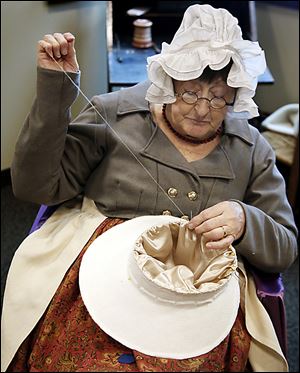 Re-enactor Jean Roberts of St. Clair Shores, Mich., sews a hat as part of the festivities.