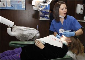 First-year pediatric dental resident Erin Knierim cleans the teeth of Khaiya Johnson, 8, of Bryan, during the Toledo Dental Society's Give Kids a Smile Day at the UT Dental Residency Program.
