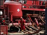  A worker steps through the maze of hoses being used at a remote fracking site being run by Halliburton for natural-gas producer Williams in Rulison, Colo. The oil and gas industry is trying to ease environmental concerns by developing nontoxic fluids for the drilling process known as fracking. But it's not clear whether the fluids will be widely embraced by drilling companies.