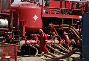 A worker steps through the maze of hoses being used at a remote fracking site being run by Halliburton for natural-gas producer Williams in Rulison, Colo. The oil and gas industry is trying to ease environmental concerns by developing nontoxic fluids for the drilling process known as fracking. But it's not clear whether the fluids will be widely embraced by drilling companies.