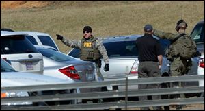 Law enforcement officials continue to work the scene of an ongoing hostage crisis in Midland City, Ala., Friday, Feb. 1, 2013. Local, state and federal officers wait out a man accused of shooting and killing a school bus driver, then snatching a 5-year-old child. Suspect Jimmy Lee Dykes has been holed up in a bunker on his property with the child since the late afternoon shooting on Tuesday, Jan. 29, 2013. (AP Photo/al.com, Julie Bennett)