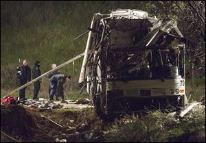 Investigators work at the scene, early today, of the accident where at least eight people were killed and 38 people were injured Sunday after a tour bus carrying Mexican tourists careened out of control while traveling down a mountain road, striking a car, flipping and plowing into a pickup truck, near Yucaipa, Calif.