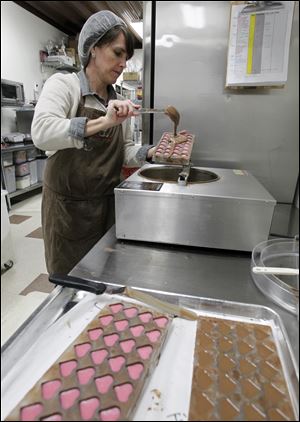 Nancy Bontrager applies a chocolate bottom to heart shaped chocolates at her Stella Leona artisan chocolates in Pettisville.