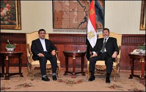 Iran's President Mahmoud Ahmadinejad, left, and Egyptian President Mohammed Morsi, right, pose for photographers in Cairo, today.