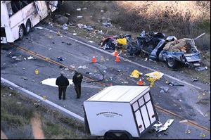 Authorities work Monday at the scene of Sunday's fatal tour bus crash on Highway 38 north of Yucaipa, Calif., that left at least eight people dead and dozens injured.