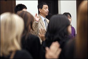 Kevin Yu, center, formerly of the United Kingdom, is among 30 immigrants who became American citizens in a ceremony in U.S. District Court in Toledo.  Another was Guillermo Vidales Gutierrez, who told about his 20-year path to citizenship on Tuesday.