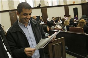 Ehab Nazem Abouadi smiles as he takes a look at his papers after being sworn in as an American in Tues-day's naturalization ceremony. He’s from Lebanon.