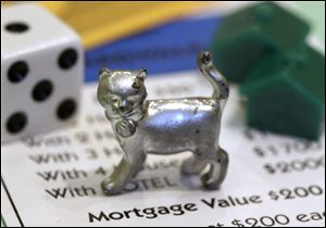The newest Monopoly token, a cat, rests on a Boardwalk deed next to a die and houses at Hasbro Inc. headquarters, in Pawtucket, R.I.