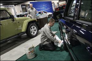 Detailer Joshua Pirrwitz, left, and Yark Automotive Group Detail Manager Karac Isom joke as they polish Jeeps before the start of the Greater Toledo Auto Show today at SeaGate Convention Centre in Toledo. The event runs through Sunday. Tickets are $6 for adults and $4 for those 55 and over.