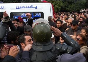 A riot police officer salutes the ambulance carrying the body of Chokri Belaid  after he was shot to death in today Tunis.