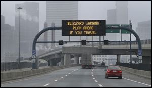 A warning sign flashes for motorists on the expressway into Boston as snow starts to fall.