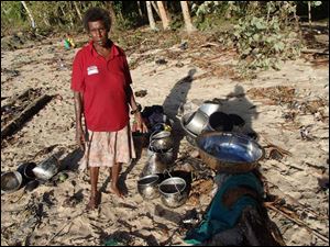 A woman stands next to her belongings she found along a beach at Venga village after tsunami hit Temotu province, Solomon Islands.