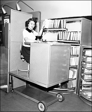 In 1953, a woman remains seated as she files paperwork using a hydraulic lift in Chicago. In the last 60 years, machines have become smarter, smaller, and more efficient.