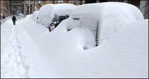 A man walks past snow covered cars in the Chinatown neighborhood of Boston.