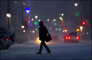 A woman crosses Congress Street during a snow storm, Friday, in Portland, Maine. 