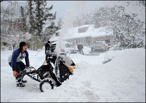 Eguin Belasquez steers a snow blower through mounds of snow as he helps his friend dig out of his driveway after a snow storm.