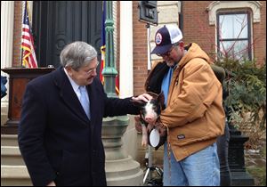 Iowa Gov. Terry Branstad, left, pardons a Berkshire pig named Bonnie, held by her owner Randy Hilleman.