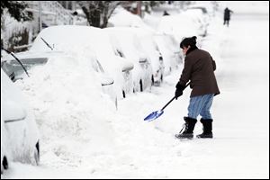 Tina Khoshaboo clears snow from her car on South Water Street during the aftermath of a blizzard in the Byram section of Greenwich, Conn., Saturday morning.