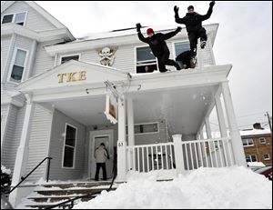From left, Worcester Polytechnic Institute freshmen Kyle Foster and Steven Como, both members of the Tau Kappa Epsilon fraternity, jump from the fraternity house porch roof into a steep snow bank on Wachusett Street in Worcester, Mass., in the aftermath of an overnight storm on Saturday.
