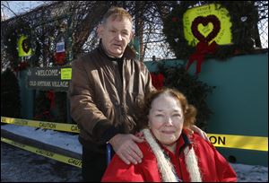 Larry and Susan Ocheske pose in front of a Sandy Hook memorial they arranged at the Old Amtrack Village site at the corner of Emerald and Logan streets in Toledo. They also provided two large Valentine cards for people to sign across the street from the memorial.