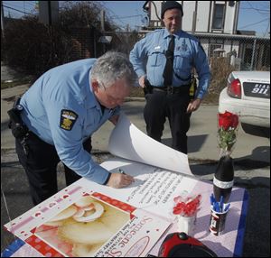 Toledo Police officers Mike Stewart, left, and Craig Smith sign cards for Sandy Hook Elementary students.