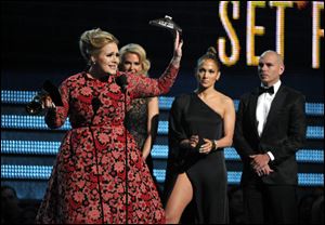 Adele, left, accepts the award for best pop solo performance for 
