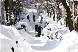 People pause while digging out their cars in Boston. Driving bans were lifted on Sunday and flights resumed at most airports. Boston's subway service was to resume partial service on Monday. 