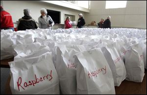 People look over different bags of flavored paczki. By 11 a.m. Sunday, about 250 dozen of the 1,500 dozen available treats made by Bakery Unlimited had sold.