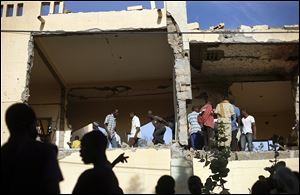 Malian people mill through the heavily shelled police station in Gao, northern Mali, Monday, one day after Mujao fighters engaged in a firefight with Malian forces. 