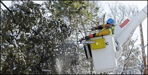Andrew Varney, a lineman from Canton, N.Y., frees a pine tree stuck in lines in Scituate, Mass. Crews raced to restore power to more than 220,000 people.