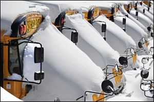 Idle school buses remain snow-covered in Hartford on Sunday. Many districts in the region closed the schools as the area continues to dig out from the massive winter storm.