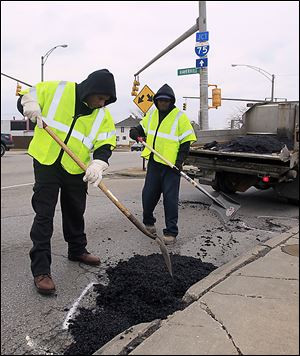  Ernest Persley, left, and Marvin Arnold, both of Toledo, working on a pothole on Phillips at Haverhill.