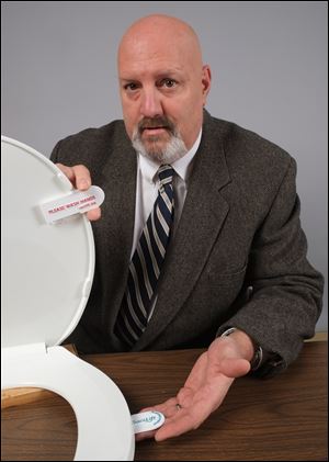David Fahrbach of Fremont displays his ‘Sanilift’ invention on Tuesday. The device is billed as a sanitary lifting device for toilet seats that he feels is perfect for any place with public restrooms.