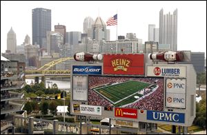 The Pittsburgh skyline looms behind the display screen at Heinz Field during an NFL football game between the Pittsburgh Steelers and the Atlanta Falcons. Billionaire Warren Buffett's Berkshire Hathaway and another investment group is acquiring the ketchup-fueled food conglomerate, H.J. Heinz Co.
