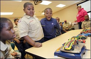 Fifth grader Jadan Turner, left, and third graders Donavan Linzy and Zarnell Dicus marvel as Donavan's pinewood derby car weighs in close to the maximum allowance during Boy Scouts at Glenwood Elementary School on Friday.