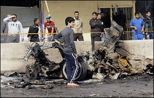 Iraqis inspect the scene of a car bomb attack in Baghdad on Sunday. A series of car bombs exploded within minutes of each other as Iraqis were out shopping.