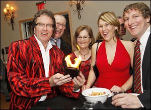 International magic champion Pattrick Przysiecki, left, entertains guests with his flaming wallet, from left, Ray and Joyce Miller, Melanie Miller, and Kevin Rantanen.