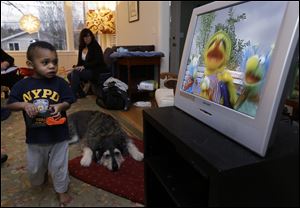 Nancy Jensen, second from left, looks on as her son Joe, 2, is given a special treat of a little TV time at their home in Seattle. 