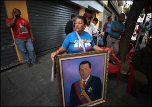 A woman holds a painting of President Hugo Chavez as supporters gather around Bolivar square after his return to the country in Caracas, Venezuela today.