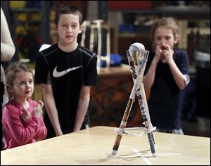Sylvania siblings Chloe, 4, Jadon, 10 and Caelyn, 7, Thompson keep their fingers crossed, hoping their ball on top of their paper tower won't be blown off by a large fan. The Thompsons participated in the Paper Tower Engineering Challenge at the Imagination Station in Toledo on Monday.