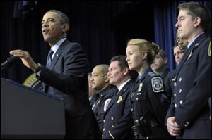 President Obama, accompanied by first responders behind him, gestures as he speaks in Washington today.