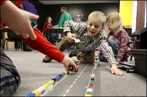 Grayson Scheub, 6, center, cheers as he pits his Lego car against another child's during a demolition derby during recent class at Build It in Perrysburg. 